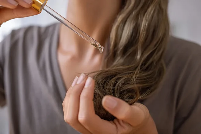 Woman gently applying hair oil before bedtime to prevent overnight hair frizz