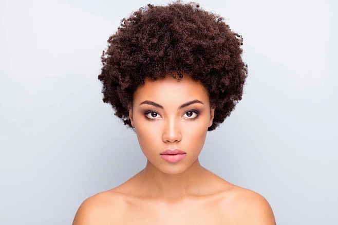 Woman with curly hair gathered loosely with a silk scrunchie in a pineapple style for sleep